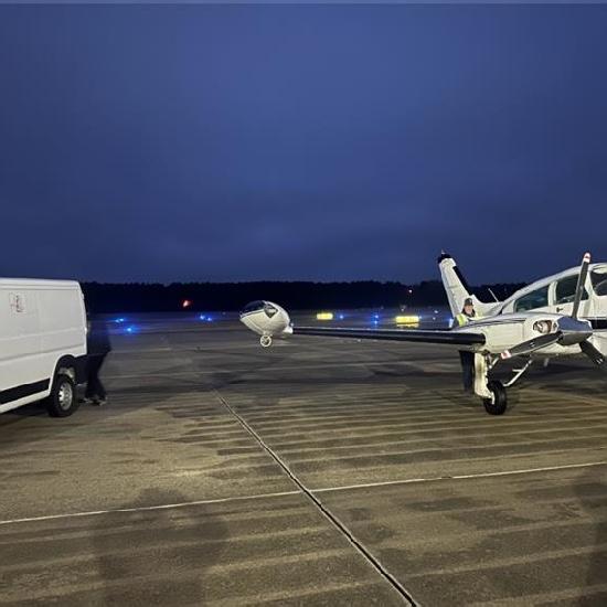 A cargo van beside a twin-engine charter aircraft on an apron at dusk.