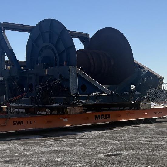 Two oversized cable reels lashed to an orange MAFI roll trailer at a port terminal.